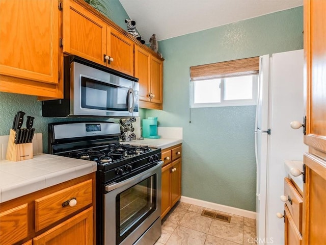 271 Vista Del Mar Unit 1, San Simeon, CA 93452 - kitchen with stainless steel appliances, tile countertops, brown cabinets, and a textured wall