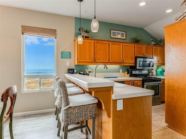 271 Vista Del Mar Unit 1, San Simeon, CA 93452 - kitchen featuring appliances with stainless steel finishes, tile countertops, a peninsula, brown cabinets, and vaulted ceiling