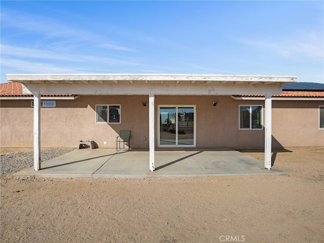 7755 7th St, Phelan, CA 92371 - back of property with a patio, stucco siding, a tile roof, and solar panels