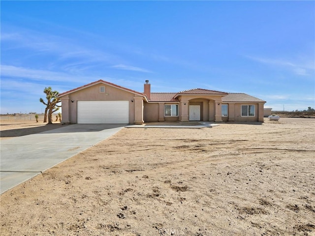 7755 7th St, Phelan, CA 92371 - view of front of home with a garage, a chimney, a tiled roof, driveway, and stucco siding
