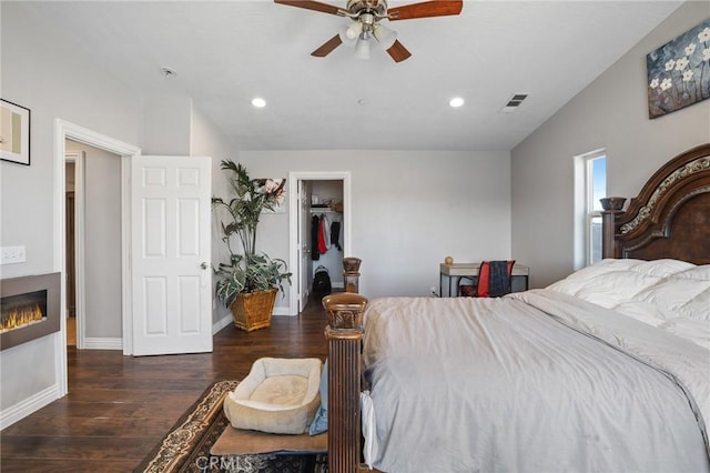 7755 7th St, Phelan, CA 92371 - bedroom featuring wood finished floors, a walk in closet, recessed lighting, a glass covered fireplace, and a ceiling fan