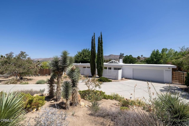 54667 Benecia Trl, Yucca Valley, CA 92284 - view of front of property featuring concrete driveway, an attached garage, and stucco siding