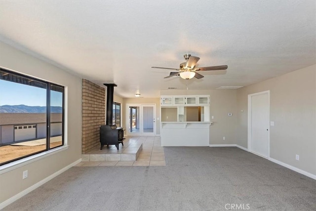 7267 Dalscote St, Hesperia, CA 92345 - unfurnished living room featuring a wood stove, light colored carpet, plenty of natural light, and a ceiling fan