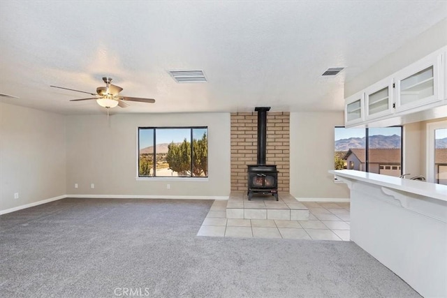 7267 Dalscote St, Hesperia, CA 92345 - unfurnished living room featuring light colored carpet, healthy amount of natural light, a wood stove, a textured ceiling, and ceiling fan