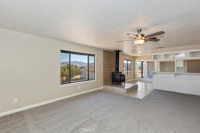7267 Dalscote St, Hesperia, CA 92345 - unfurnished living room with a wood stove, light carpet, ceiling fan, a textured ceiling, and a mountain view