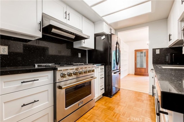 966 Willow Creek Rd Unit 14, Lake Arrowhead, CA 92352 - kitchen with stainless steel stove, under cabinet range hood, white cabinets, tasteful backsplash, and dark stone counters