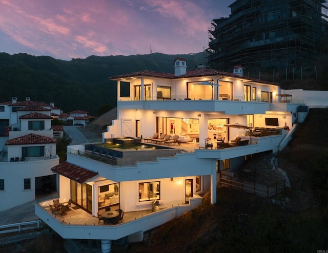 211 Mar De Cortez, Avalon, CA 90704 - back of house at dusk featuring stucco siding, a chimney, and a balcony