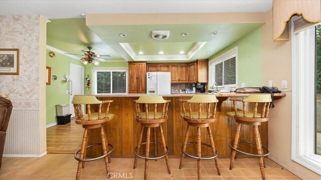 860 Knollwood Dr, Corona, CA 92882 - kitchen with white fridge with ice dispenser, brown cabinets, a peninsula, a ceiling fan, and light countertops