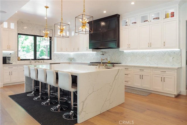 5225 Topeka Dr, Tarzana, CA 91356 - kitchen featuring a kitchen island with sink, premium range hood, light wood-style flooring, white cabinetry, and recessed lighting