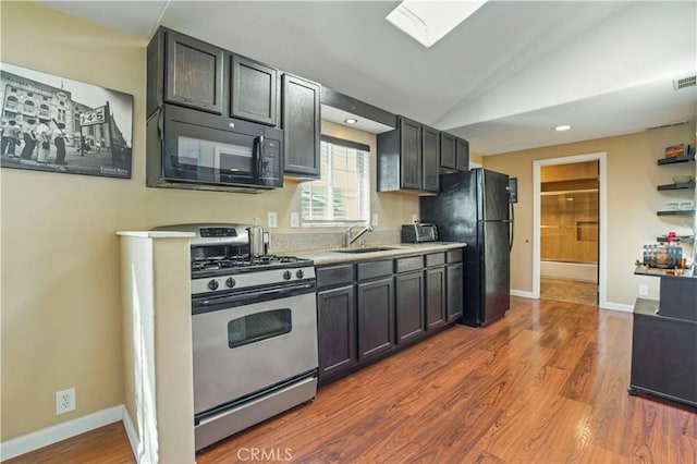 936 Gonzales St, Placentia, CA 92870 - kitchen with black appliances, light countertops, lofted ceiling, wood finished floors, and a skylight