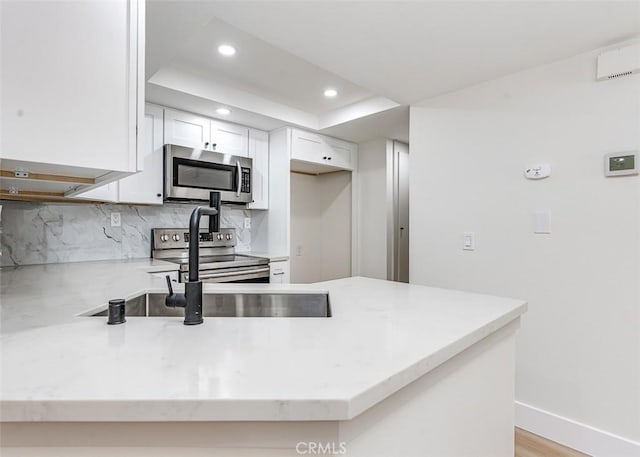 12601 Edgemont Ln Unit 40, Garden Grove, CA 92845 - kitchen featuring appliances with stainless steel finishes, a peninsula, recessed lighting, light stone countertops, and white cabinetry