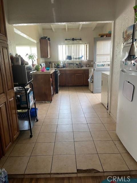 1408 S Central Ave, Compton, CA 90220 - kitchen with light tile patterned floors, beamed ceiling, washing machine and clothes dryer, light countertops, and fridge