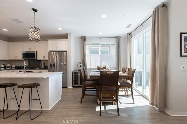 45055 Via Vela, Temecula, CA 92592 - kitchen featuring appliances with stainless steel finishes, light wood-style flooring, white cabinetry, a kitchen bar, and light countertops