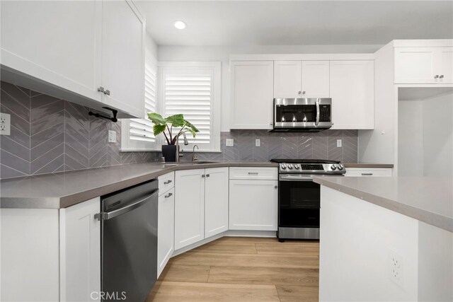 6508 Alondra Blvd, Paramount, CA 90723 - kitchen featuring stainless steel appliances, white cabinetry, light wood-type flooring, backsplash, and recessed lighting