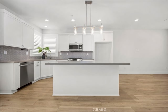 6508 Alondra Blvd, Paramount, CA 90723 - kitchen with stainless steel appliances, white cabinets, decorative backsplash, a center island, and hanging light fixtures