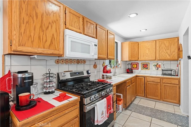 1876 Sparrow Rd, Wrightwood, CA 92397 - kitchen featuring stainless steel gas range, white microwave, tile countertops, tasteful backsplash, and light tile patterned flooring
