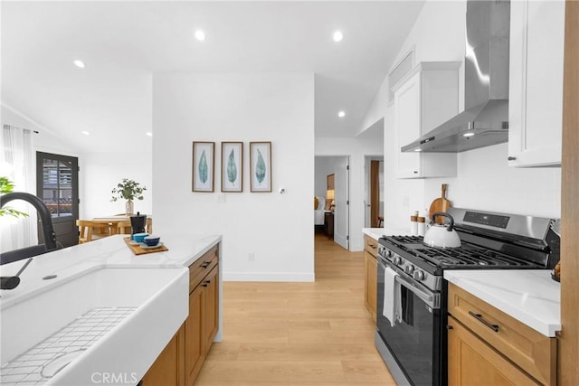 351 Vista Pl, Los Angeles, CA 90042 - kitchen with gas range, wall chimney range hood, light wood finished floors, recessed lighting, and white cabinetry