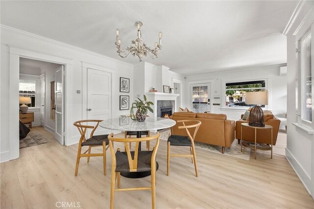 1111 Dawson Ave, Long Beach, CA 90804 - dining area featuring a lit fireplace, a chandelier, light wood-style floors, ornamental molding, and a wall mounted air conditioner