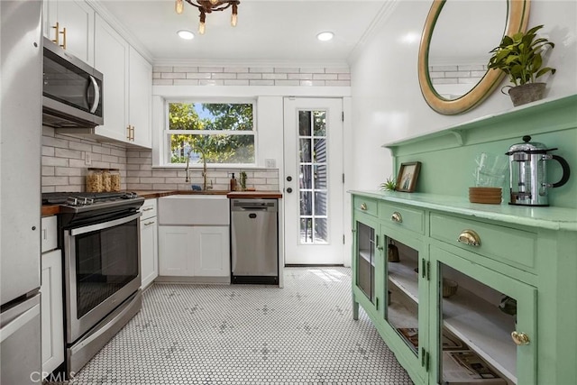 1111 Dawson Ave, Long Beach, CA 90804 - kitchen with appliances with stainless steel finishes, white cabinets, backsplash, ornamental molding, and butcher block counters