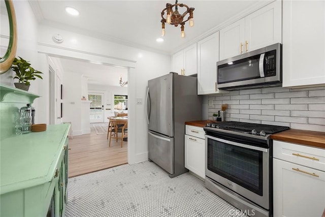 1111 Dawson Ave, Long Beach, CA 90804 - kitchen with appliances with stainless steel finishes, butcher block countertops, white cabinets, a chandelier, and crown molding
