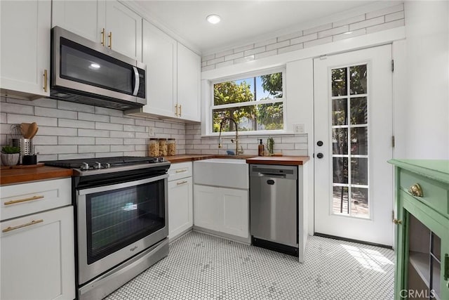 1111 Dawson Ave, Long Beach, CA 90804 - kitchen with appliances with stainless steel finishes, butcher block countertops, decorative backsplash, and white cabinets