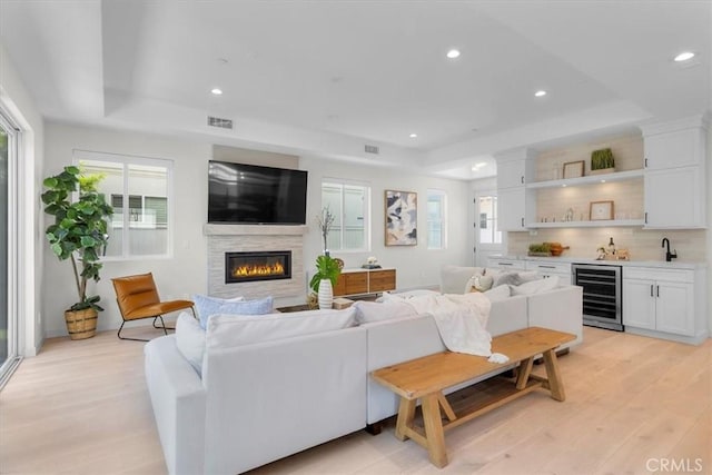 2117 Marshallfield Ln Unit B, Redondo Beach, CA 90278 - living area featuring beverage cooler, bar with sink, a raised ceiling, light wood-style floors, and a glass covered fireplace