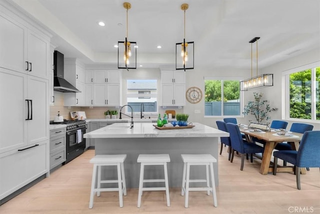 2117 Marshallfield Ln Unit B, Redondo Beach, CA 90278 - kitchen featuring high end range, wall chimney range hood, a kitchen breakfast bar, light wood-style flooring, and white cabinets