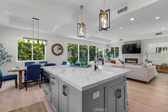2117 Marshallfield Ln Unit B, Redondo Beach, CA 90278 - kitchen featuring a tray ceiling, gray cabinets, light wood finished floors, a glass covered fireplace, and recessed lighting