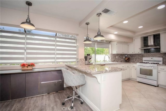 7008 Davenport Ct, Rancho Cucamonga, CA 91701 - kitchen featuring gas range gas stove, wall chimney exhaust hood, white cabinetry, a peninsula, and tasteful backsplash