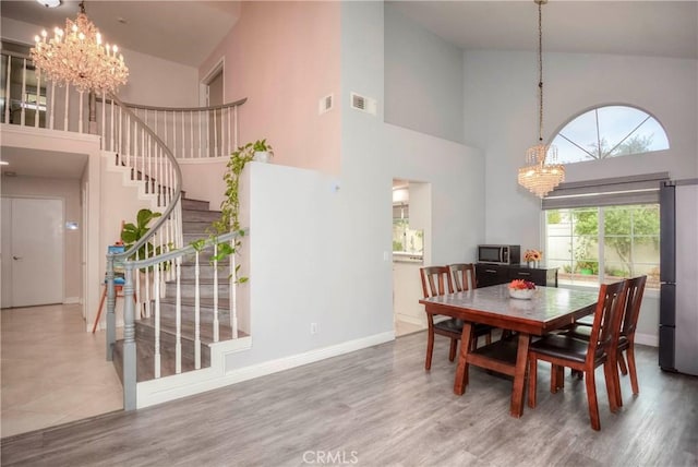 7008 Davenport Ct, Rancho Cucamonga, CA 91701 - dining area featuring a chandelier, a towering ceiling, stairway, and wood finished floors