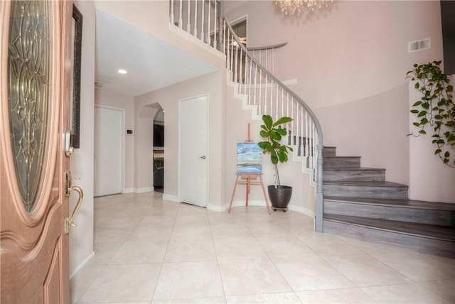 7008 Davenport Ct, Rancho Cucamonga, CA 91701 - foyer entrance with arched walkways, stairs, light tile patterned flooring, a high ceiling, and recessed lighting