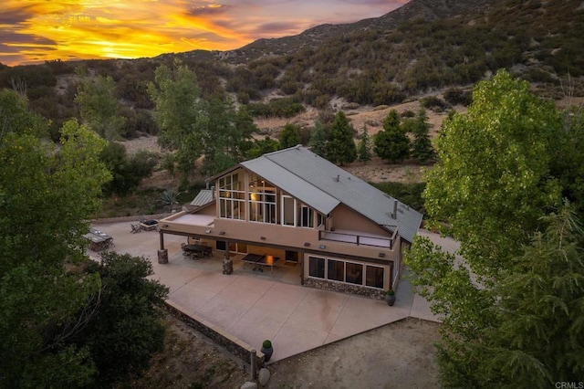 26380 San Felipe Rd, Warner Springs, CA 92086 - back of property at dusk featuring a patio, a mountain view, stucco siding, and a metal roof