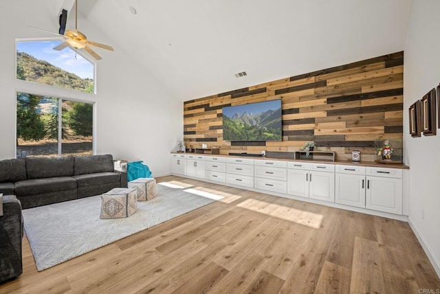 26380 San Felipe Rd, Warner Springs, CA 92086 - living room with high vaulted ceiling, wooden walls, light wood-style flooring, a ceiling fan, and an accent wall