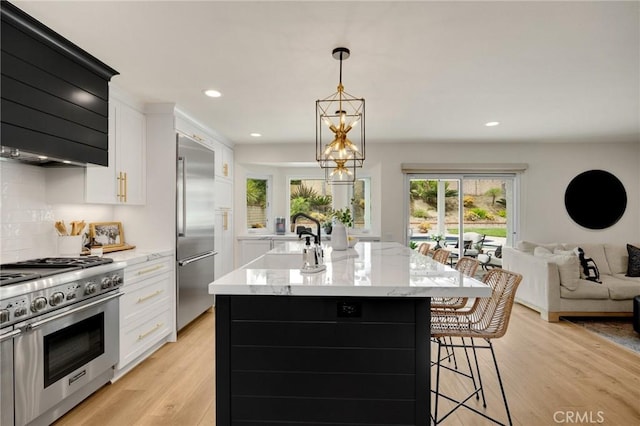 637 Silver Bridle Rd, Walnut, CA 91789 - kitchen featuring premium appliances, a kitchen island with sink, open floor plan, white cabinets, and light wood-type flooring