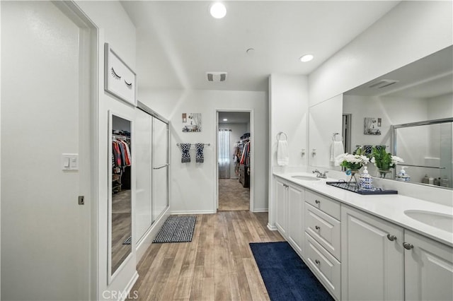 14160 Hercules St, Hesperia, CA 92345 - bathroom with a walk in closet, a stall shower, double vanity, wood finished floors, and recessed lighting
