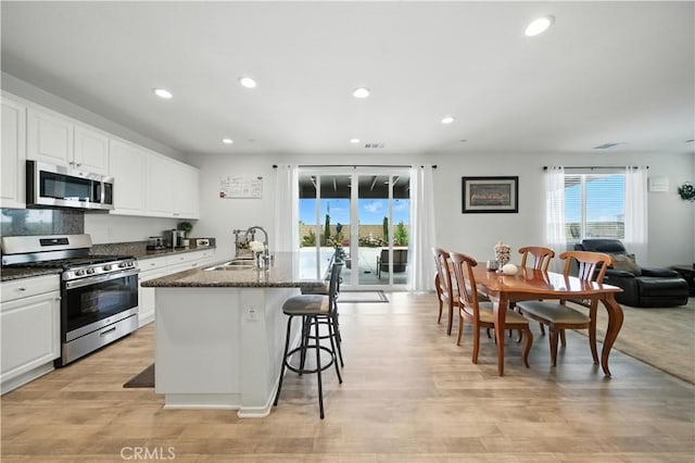14160 Hercules St, Hesperia, CA 92345 - kitchen with stainless steel appliances, recessed lighting, a kitchen bar, an island with sink, and light wood-style flooring