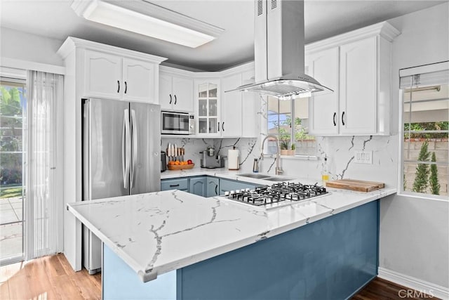 14508 S Corlett Ave, Compton, CA 90220 - kitchen with island exhaust hood, stainless steel appliances, a peninsula, light stone countertops, and light wood-style flooring