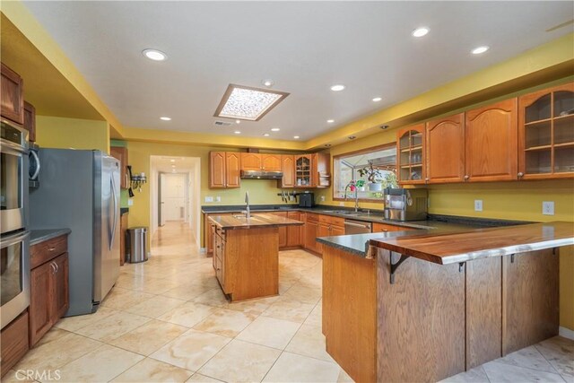 2935 Athel Dr, Hacienda Heights, CA 91745 - kitchen featuring a peninsula, appliances with stainless steel finishes, under cabinet range hood, brown cabinetry, and recessed lighting