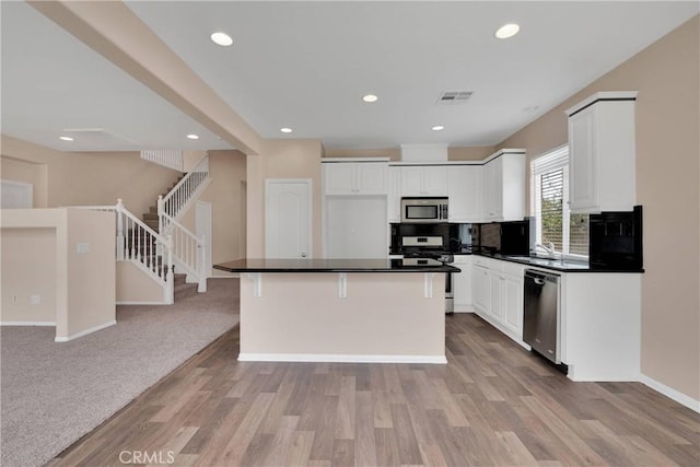 35668 Trevino Trl, Beaumont, CA 92223 - kitchen with appliances with stainless steel finishes, dark countertops, white cabinetry, light wood-style floors, and backsplash