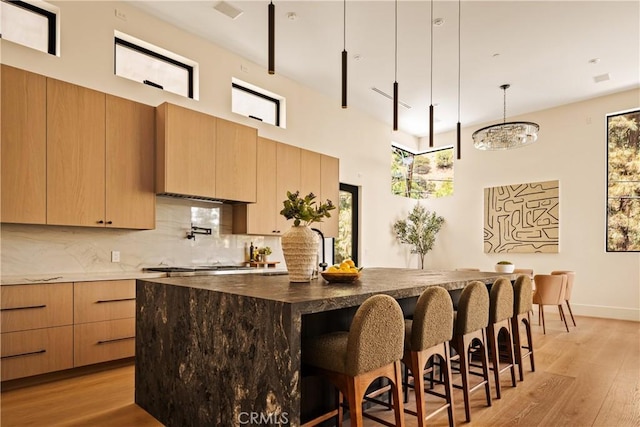 1955 Curson Pl, Los Angeles, CA 90046 - kitchen featuring a breakfast bar, light wood-style flooring, tasteful backsplash, and a center island