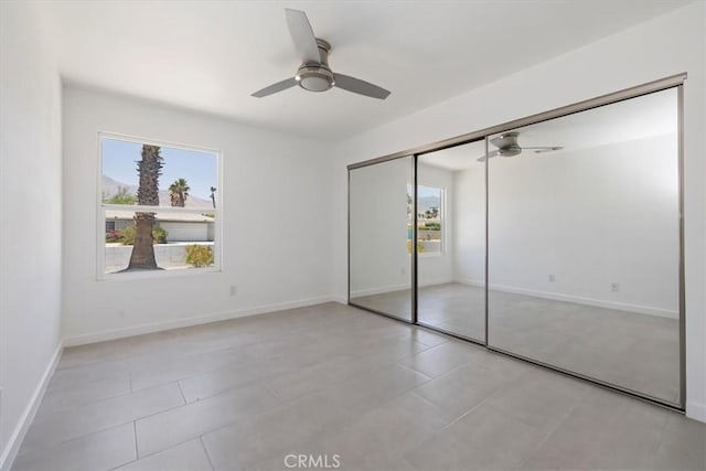 2002 N Whitewater Club Dr N, Palm Springs, CA 92262 - unfurnished bedroom with multiple windows, a closet, light tile patterned floors, and a ceiling fan