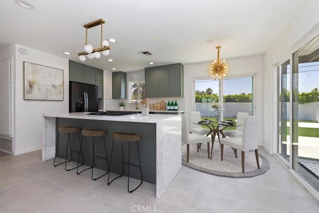 2002 N Whitewater Club Dr N, Palm Springs, CA 92262 - kitchen with black refrigerator with ice dispenser, light countertops, a kitchen bar, backsplash, and decorative light fixtures