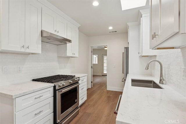 2141 Sierra Way, San Luis Obispo, CA 93401 - kitchen with appliances with stainless steel finishes, under cabinet range hood, white cabinetry, tasteful backsplash, and light wood-style flooring