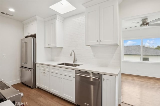2141 Sierra Way, San Luis Obispo, CA 93401 - kitchen with stainless steel appliances, a skylight, wood finished floors, tasteful backsplash, and light countertops