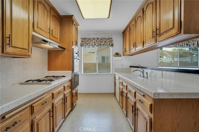18944 Prairie St, Northridge, CA 91324 - kitchen with white appliances, brown cabinets, under cabinet range hood, and light countertops