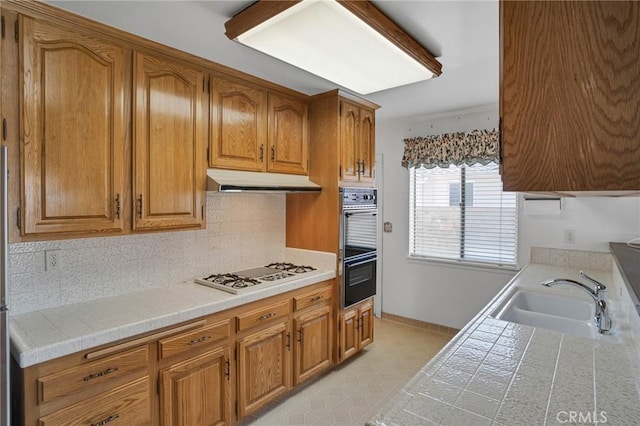 18944 Prairie St, Northridge, CA 91324 - kitchen with white gas stovetop, under cabinet range hood, brown cabinetry, and tasteful backsplash