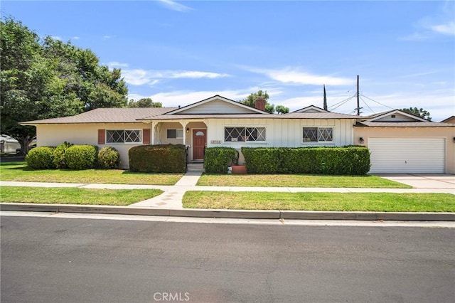18944 Prairie St, Northridge, CA 91324 - view of front of house with driveway, a front yard, board and batten siding, and a garage