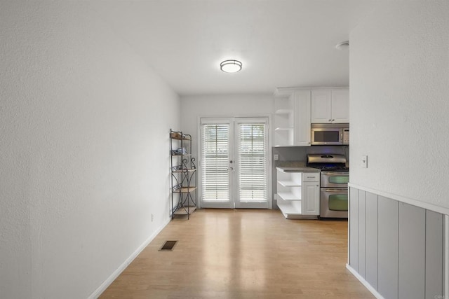 3168 Florine Dr, Lemon Grove, CA 91945 - kitchen featuring stainless steel appliances, open shelves, light wood-style floors, white cabinets, and a textured wall