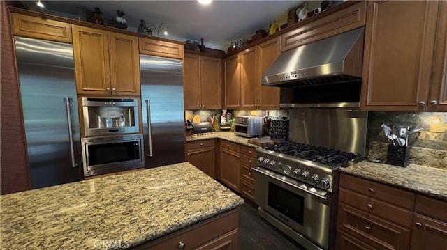 28107 Graciosa St, Valencia, CA 91355 - kitchen with extractor fan, built in appliances, tasteful backsplash, light stone countertops, and brown cabinets
