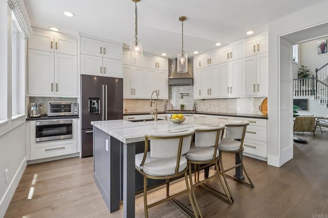 5414 Foxtail Loop, Carlsbad, CA 92010 - kitchen featuring high end refrigerator, wall chimney exhaust hood, oven, wood finished floors, and recessed lighting